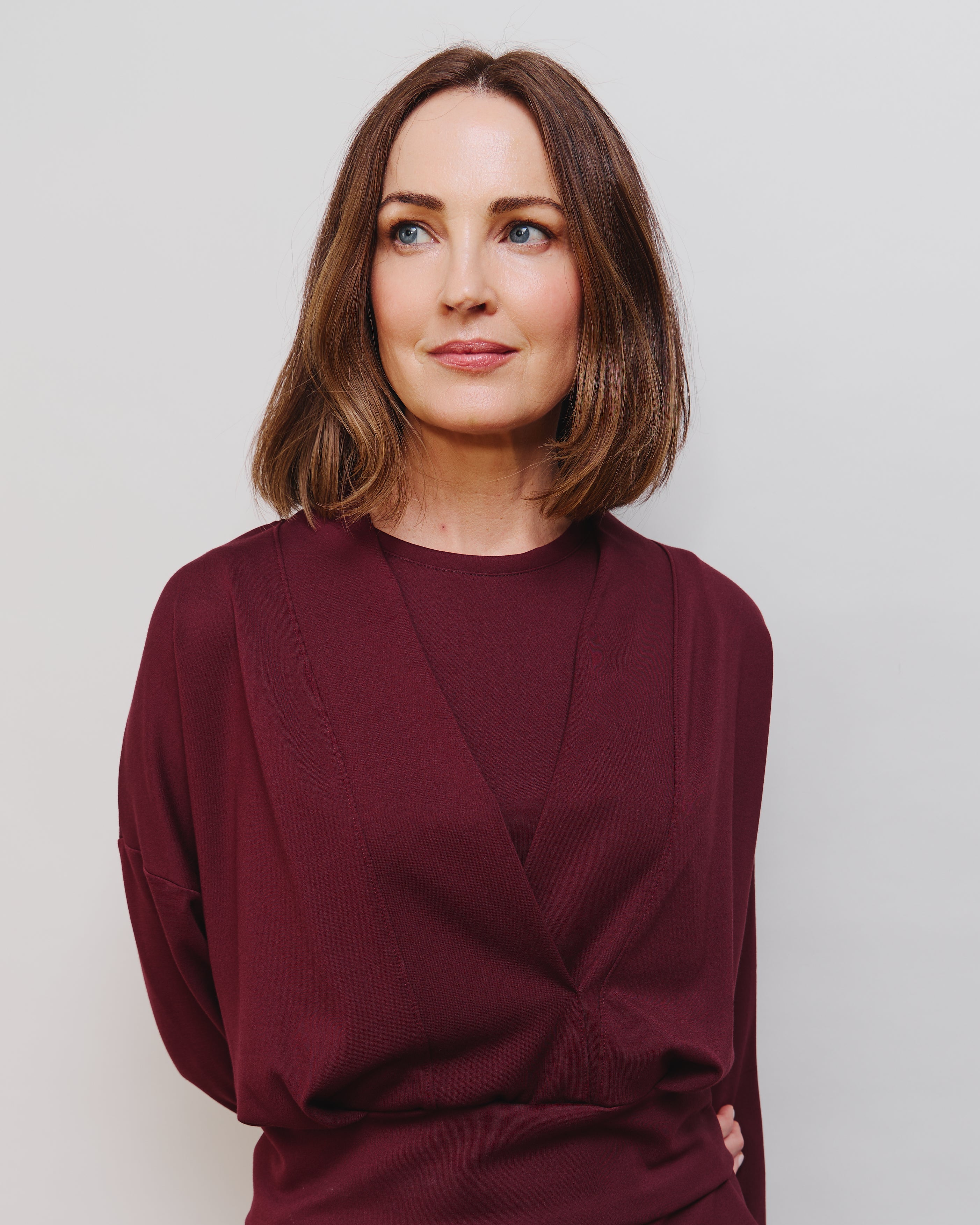 Woman wearing a burgundy outfit against a plain background